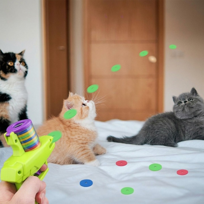 trois chats sur lit jouant avec lanceur de disques jouets pour les chats
